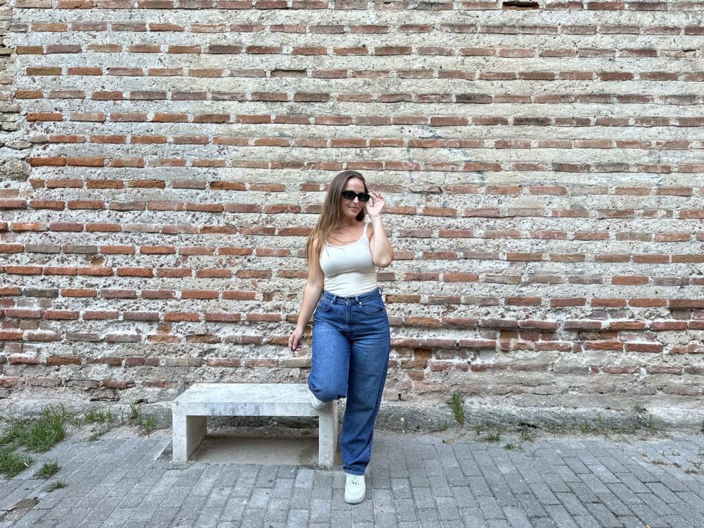 danielle in jeans and sunglasses with brick wall